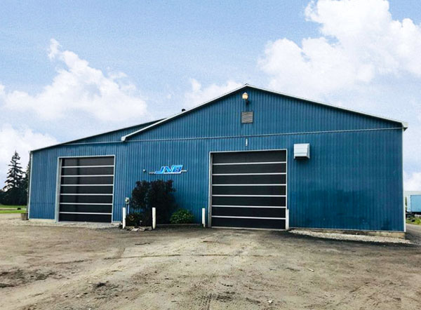 A blue building with dual garage doors, under a bright blue sky.